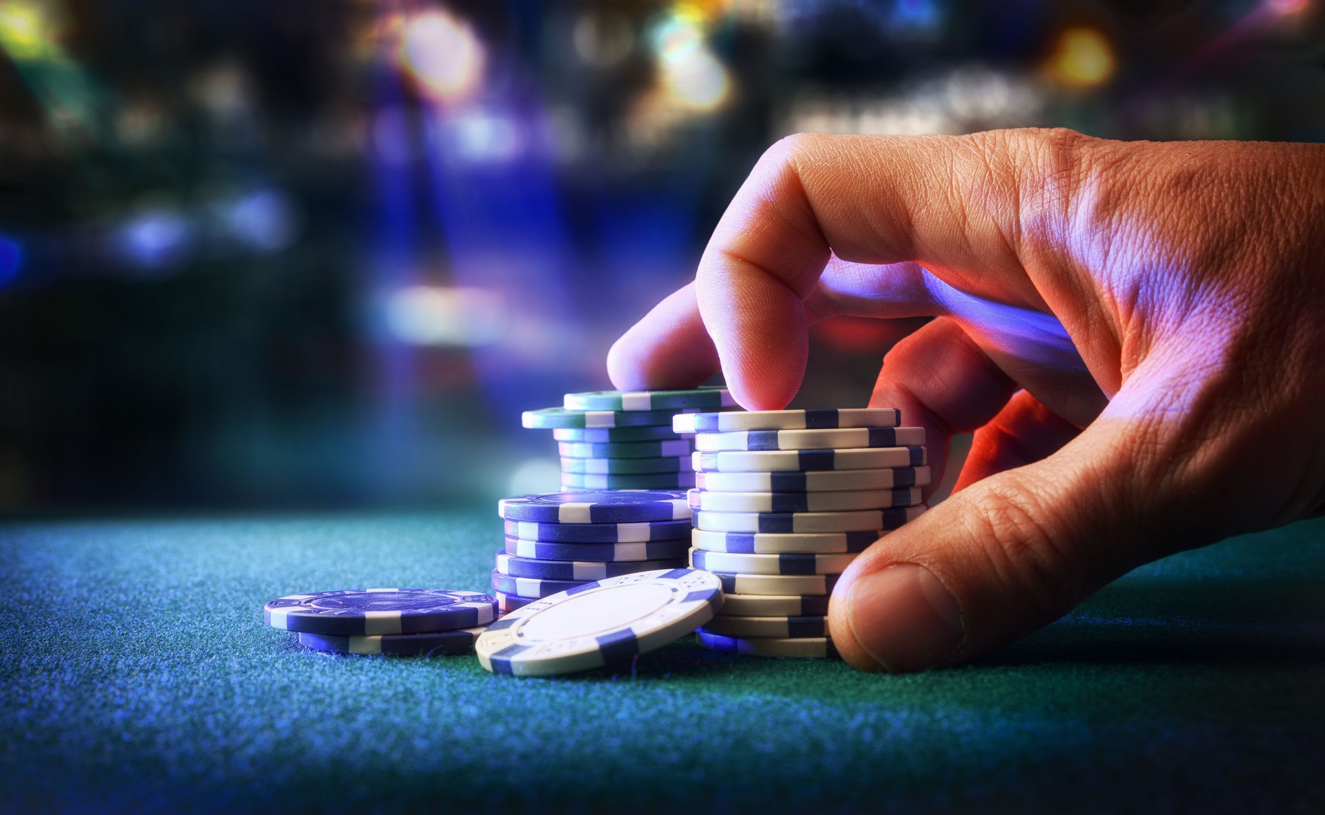 Hand betting game chips with game room in the background